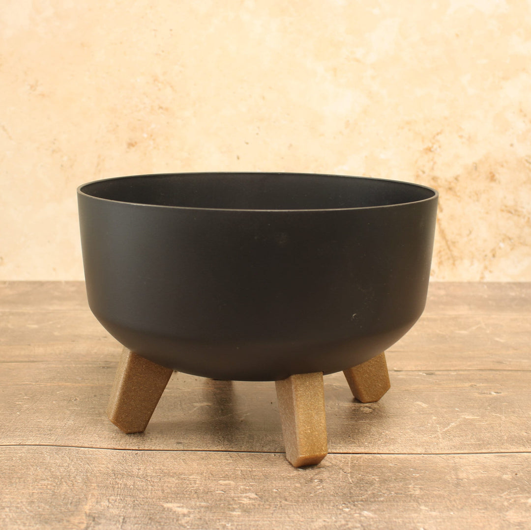 Low plant pots with legs in  anthracite, displayed on a wooden surface.