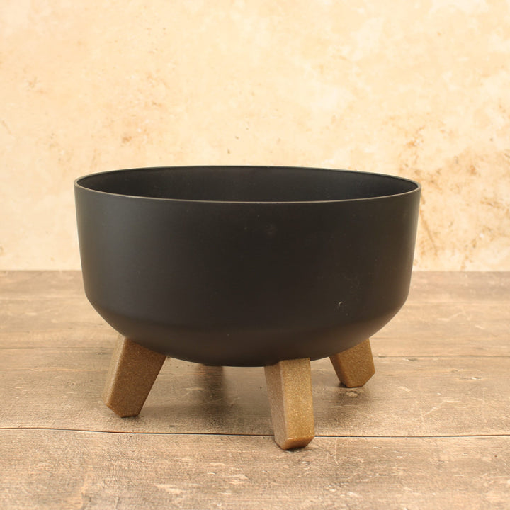 Low plant pots with legs in  anthracite, displayed on a wooden surface.