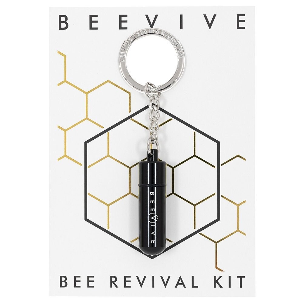 A Bee Revival Kit with a black-colored tube keychain and a gold-colored cap