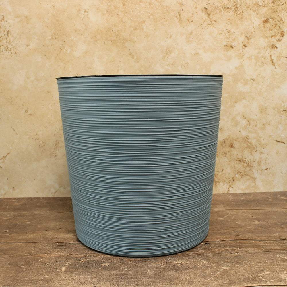 Blue round ribbed plant pot on wooden table cream background