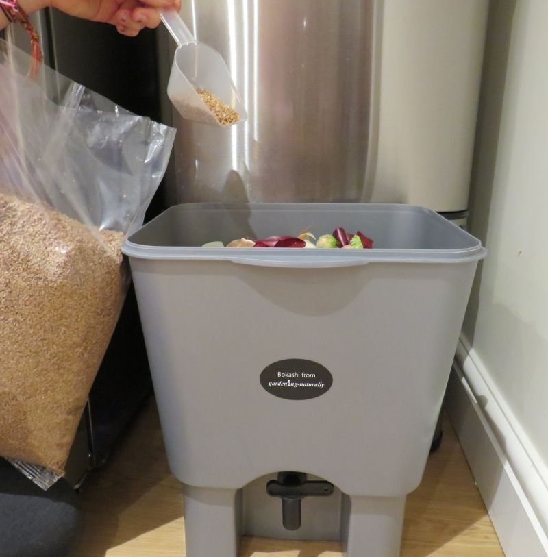 Adding bran to bokashi bin in kitchen