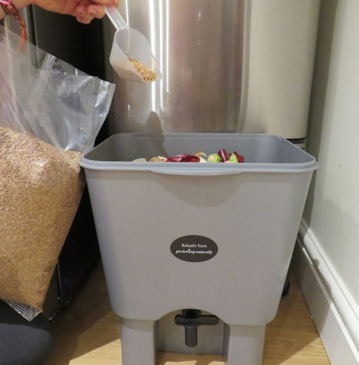 Adding bran to bokashi bin in kitchen