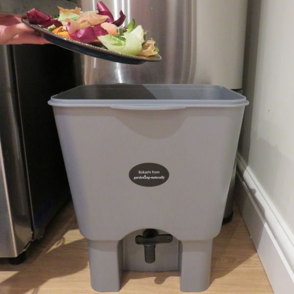 Someone adding scraps to bokashi bin