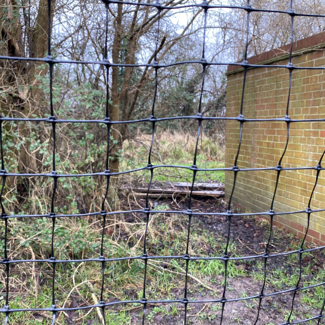 Black netting fence netting installed outdoors in a garden.
