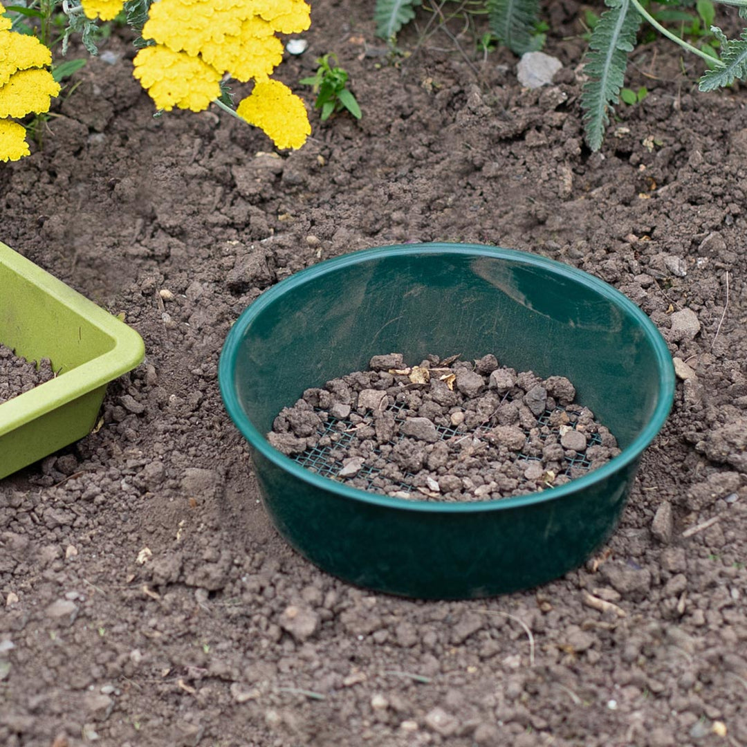 Garden sieve on soil in the garden with stones left in it