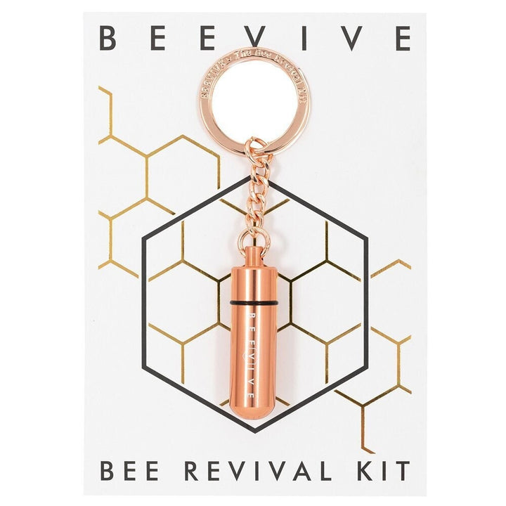 A Bee Revival Kit with a gold-colored tube keychain and a gold-colored 
