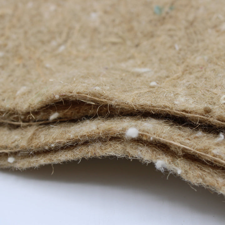 A close-up of a folded, textured tan or beige felt fabric with visible white fibres 