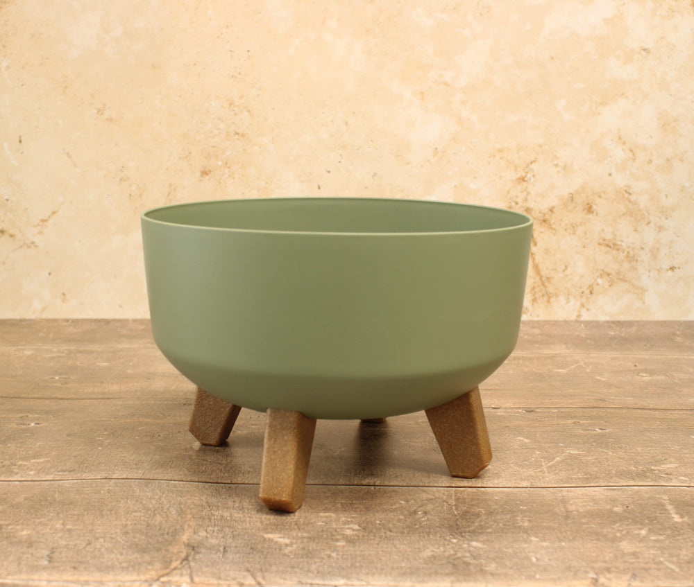 Low plant pots with legs in green, displayed on a wooden surface.