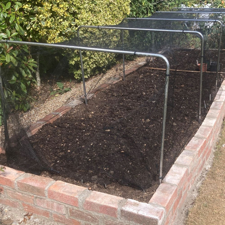 Square garden hoops with black butterfly netting in a garden