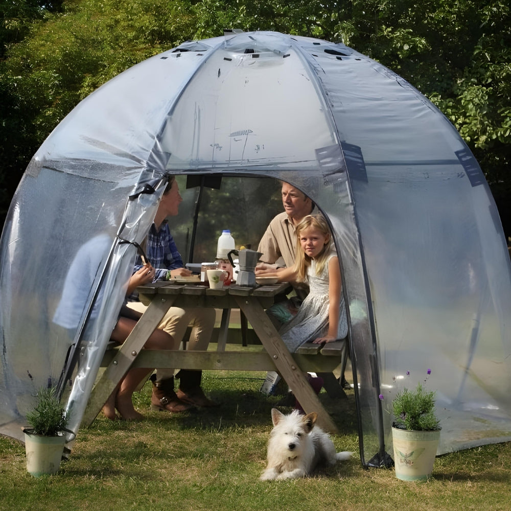 A transparent greenhouse dome with a family inside sitting around a table