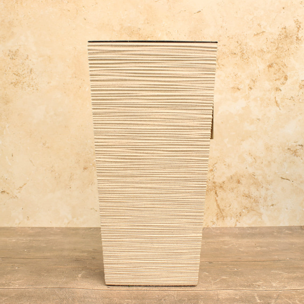Tall, ribbed ceramic planter on a wooden surface with a beige marble background