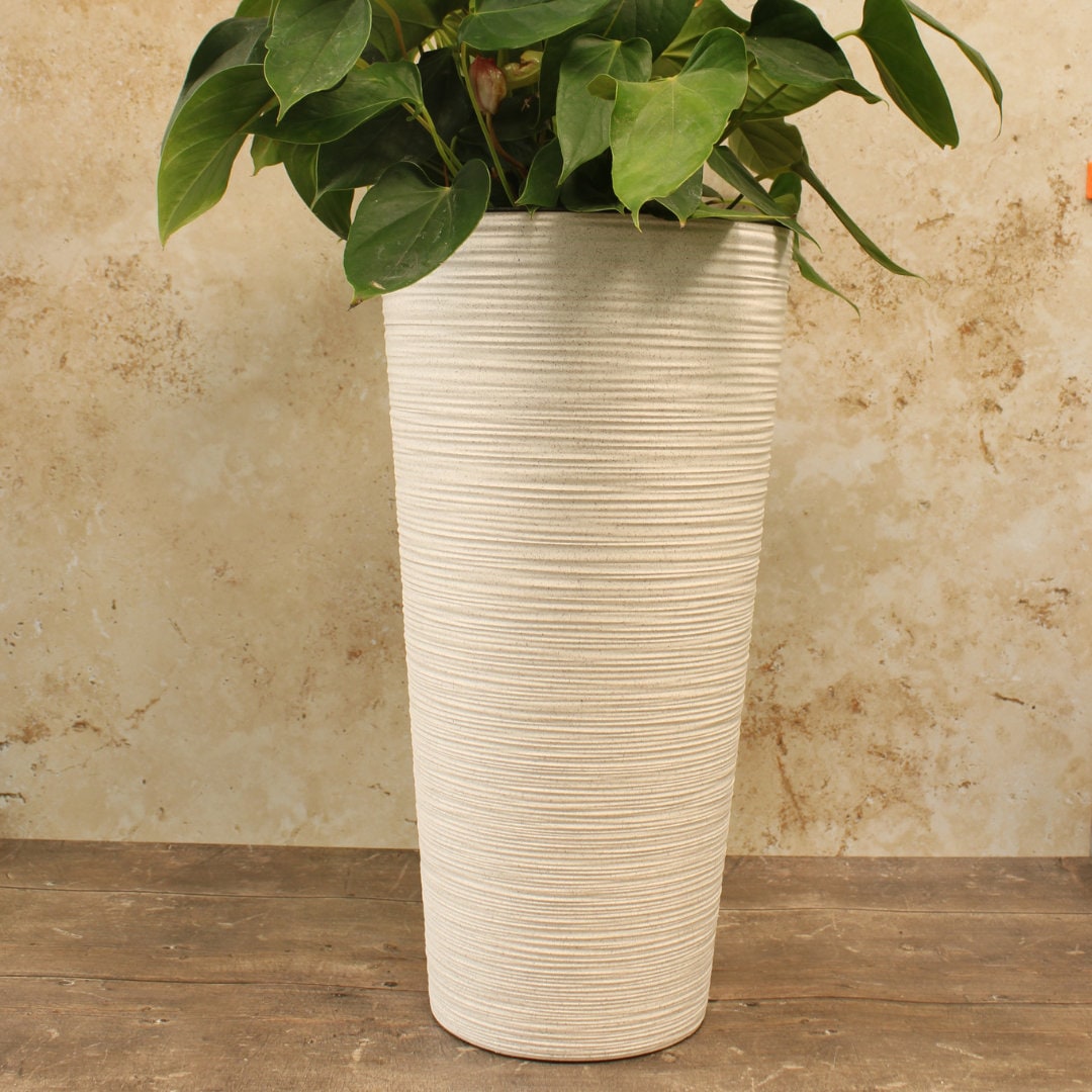 A tall round white plant pot made of recycled plastic with a plastic insert, 