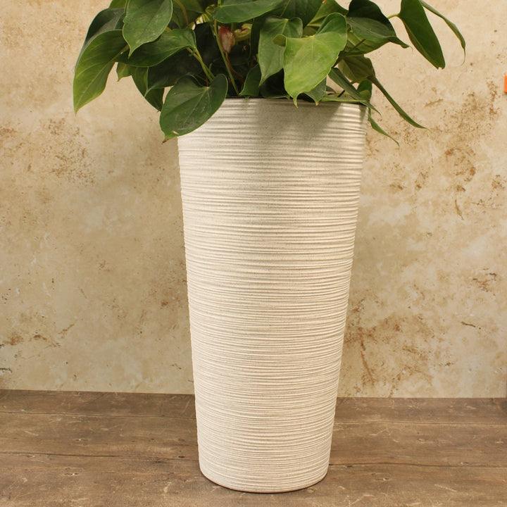 A tall round white plant pot made of recycled plastic with a plastic insert, 